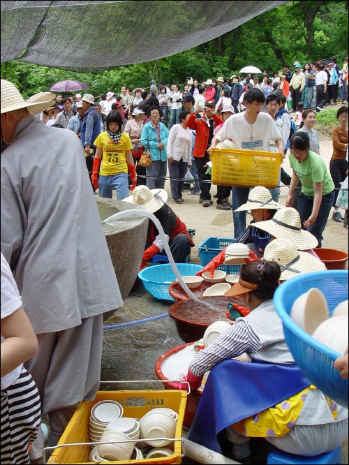 설겆이를 하는 보살들 뒤로 점심을 기다리는 사람들의 긴 줄이 보인다. 